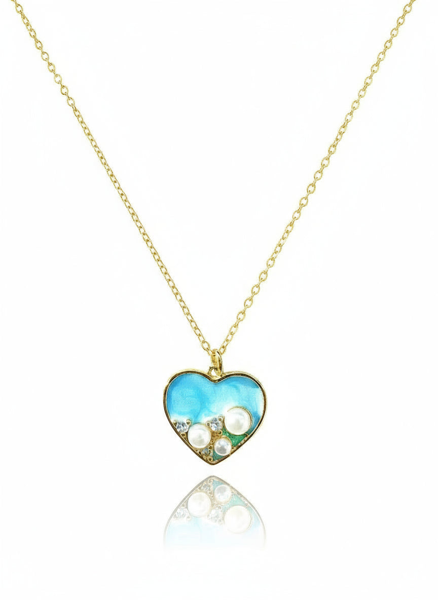 Heart-shaped pendant necklace with blue heart design on a gold chain against a white background