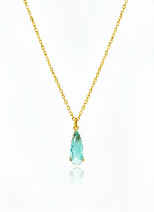Gold necklace with a blue teardrop pendant on a white background