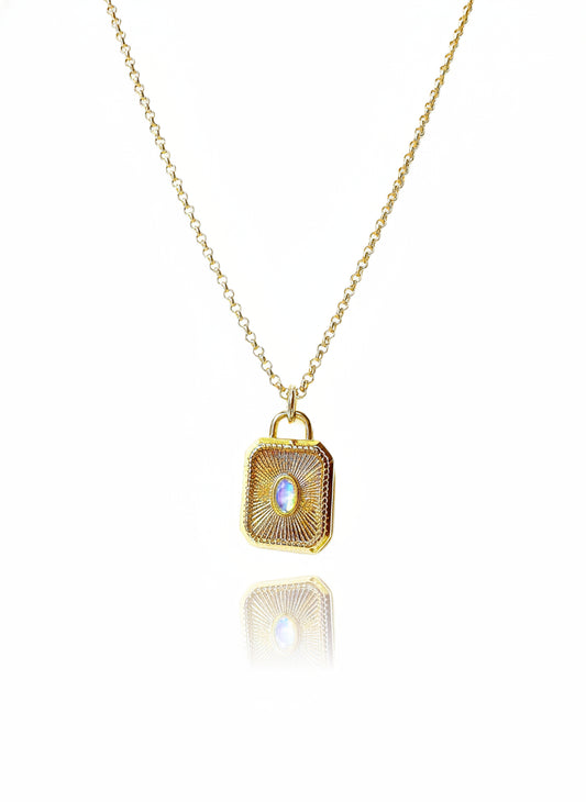 A gold-filled necklace with a square pendant featuring a moonstone solitaire, suspended on a chain with a extender.
