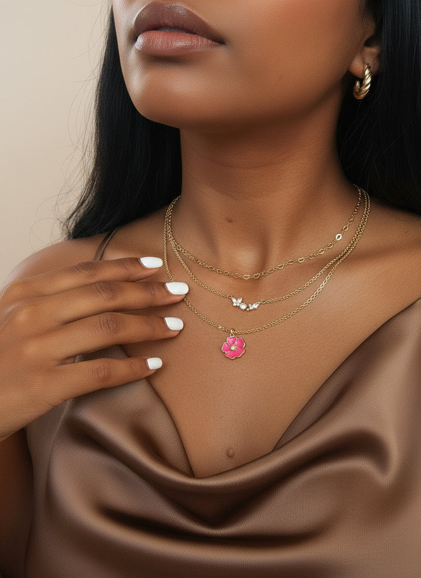 Woman wearing a gold necklace with a pink flower pendant against a neutral background
