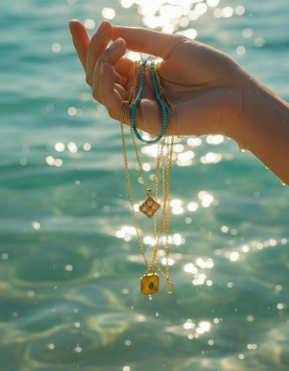 Two gold necklaces with pendants on a white background