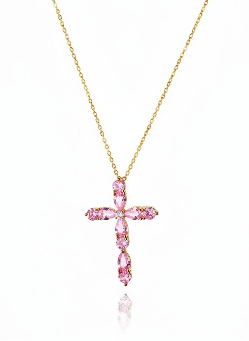 Gold necklace with a pink cross pendant on a white background