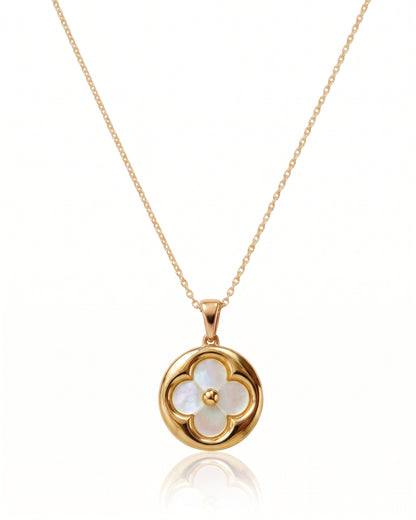 A gold chain necklace with a circular pendant featuring a four-petal flower design made of iridescent white mother-of-pearl, with a small gold center, shown on a white background with a soft reflection below. Similar to Van Cleef and Arpels necklace.