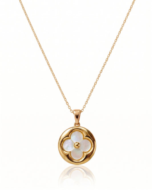 A gold chain necklace with a circular pendant featuring a four-petal flower design made of iridescent white mother-of-pearl, with a small gold center, shown on a white background with a soft reflection below. Similar to Van Cleef and Arpels necklace.