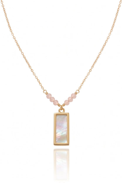 A delicate gold chain necklace featuring a vertical rectangular pendant with an iridescent mother-of-pearl inlay, accented by small pink beads along the chain, shown on a white background with a soft reflection.