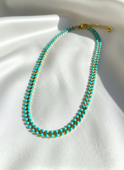 Turquoise and gold beaded necklace on a white background